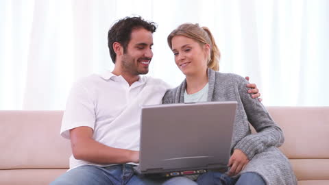 Couple Relaxing on Couch While Browsing Laptop at Home