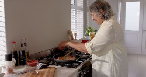 Senior woman cooking healthy meal in bright kitchen