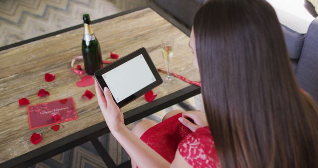 Caucasian woman with champagne making valentine's day image call on tablet, copy space on screen. valentine's day celebration, romance and communication technology.
