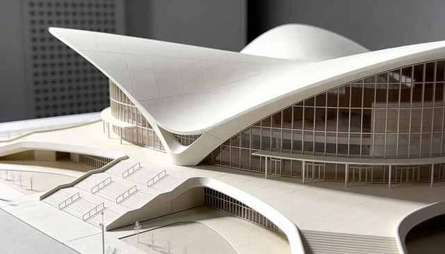 Curvilinear architectural model featuring sweeping white roof, glass facade and terraces
