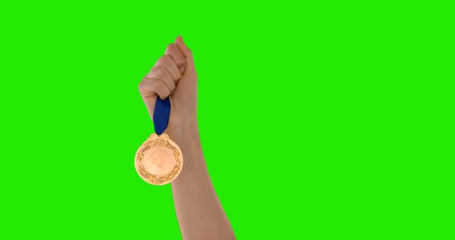 A person's hand is raised, holding a gold medal against a green background, with copy space - Download Free Stock Photos Pikwizard.com