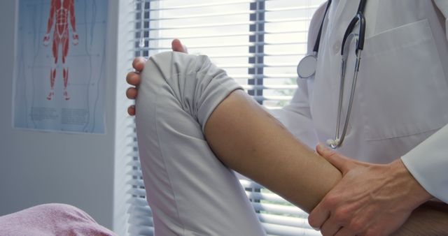 A healthcare professional examining a patient's knee in a medical office. The image depicts a focused physician holding the knee for assessment, implying the provision of medical care or diagnosis. This can be used for health-related publications, orthopedic services, medical website illustrations, health insurance advertisements, and informative material on knee injuries or general medical check-ups.