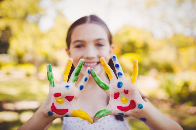 Portrait of a girl with make-up showing her painted hands in a park