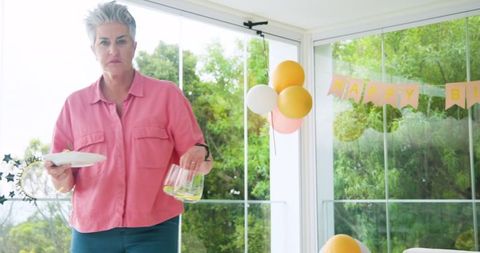 Senior Woman Cleaning After Birthday Party with Balloons and Decorations