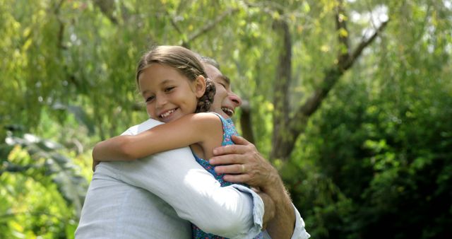 A young girl embraces a middle-aged man in a heartfelt hug, surrounded by lush greenery, with copy space. Their joyful expressions convey a sense of family love and the importance of close relationships.