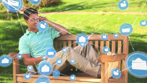 Man Relaxing in Park Using Smartphone Surrounded by Digital Icons