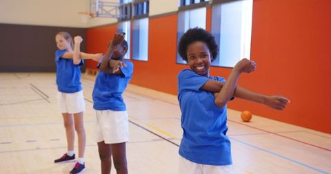 Diverse Schoolgirls Stretching in Gym for Basketball Practice