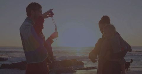Family bonding at sunset on rocky shore with pet dog