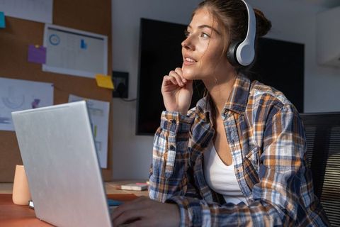 Focused Woman Using Laptop with Headphones at Home Office Desk