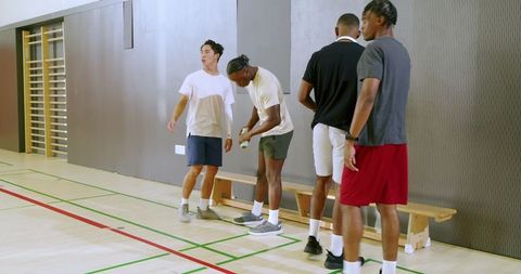 Young men standing by bench preparing for indoor court training and team drills