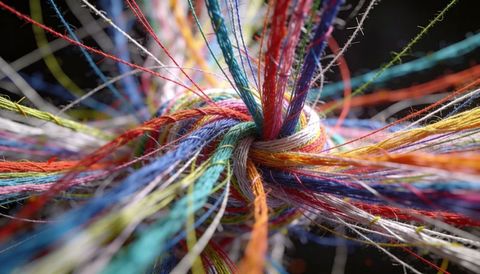 Forming multicolored thread knot showing tight weave macro texture and vibrant fibers