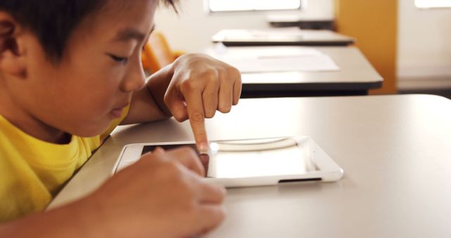 Boy interacting with tablet in classroom setting. useful for depicting digital education, modern learning tools, technology in schools, and online learning resources.