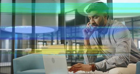 Indian Man Working with Laptop and Smartphone in Modern Office