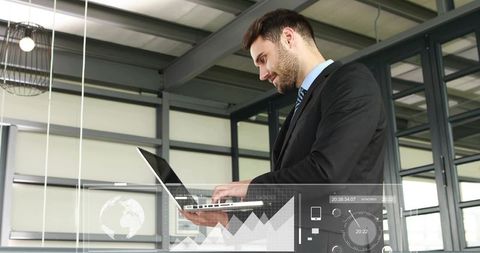 Businessman typing on laptop with virtual analytics overlay in modern office