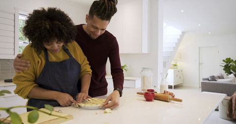 Couple baking lattice pie together on bright modern kitchen island, cozy home baking