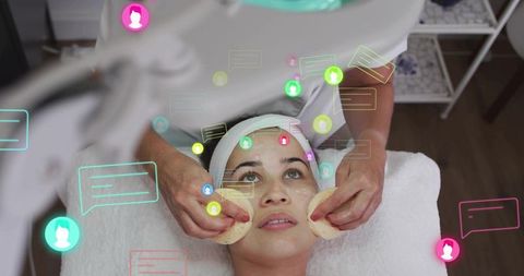 Woman receiving professional facial treatment with sponges and social media chat overlay