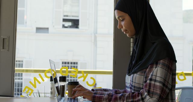 Hijab-Wearing Woman Typing on Laptop at Bright Office Workspace - Download Free Stock Images Pikwizard.com