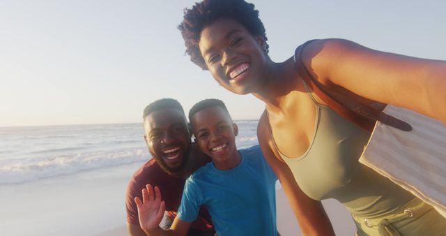 Family is enjoying a day at the beach, taking a selfie with the ocean in the background. Perfect for promoting travel, family vacations, summer holidays, and outdoor activities.