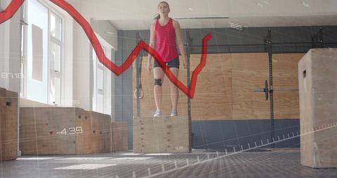 Woman standing on wooden box in gym with data overlay