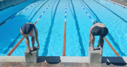 Swimmers on starting blocks in outdoor lap pool