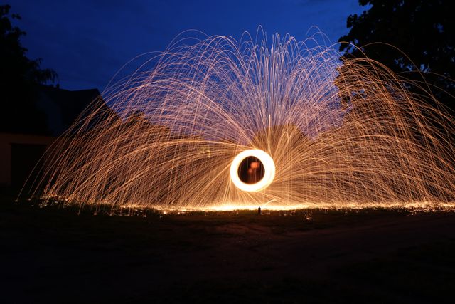 Capturing a mesmerizing night scene with long exposure photography, depicting vibrant sparks forming circular patterns. Suitable for backgrounds, digital art projects, promotional materials, or decorations emphasizing creativity and dynamic movement.