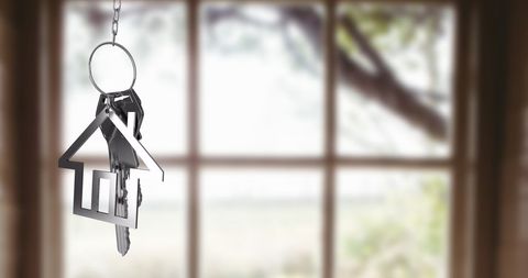 House-shaped Keychain with Keys in Front of Blurred Window