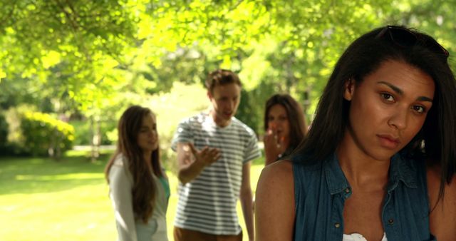 Upset Young Woman Standing Apart from Group of Friends in Park - Download Free Stock Images Pikwizard.com