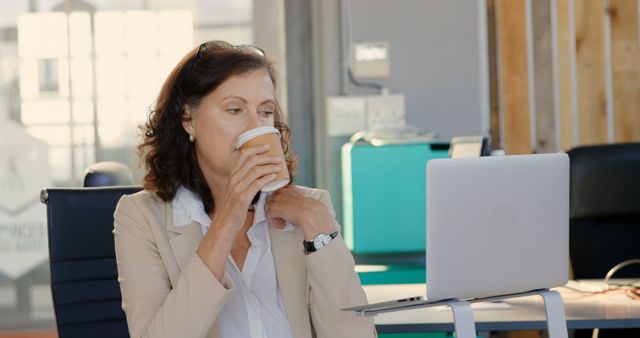 Caucasian woman enjoys a coffee break at the office. She's taking a moment to relax amidst her busy work schedule.