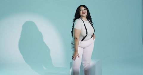 Elegant woman posing confidently in teal spotlight minimalistic studio