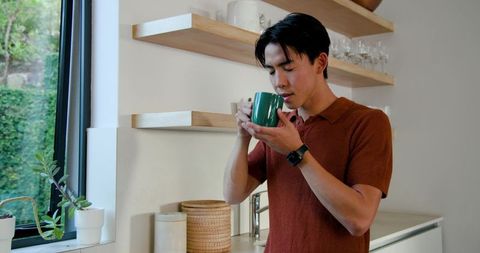 Man savoring aroma from mug in modern kitchen setting