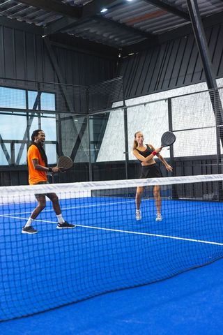 Diverse Partners Playing Enthusiastic Game on Padel Court Indoors