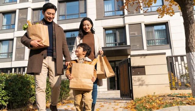 Smiling family walking home with groceries and baguette, autumn urban lifestyle
