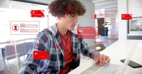 Young man working on laptop using digital security interface with red ui overlays at home