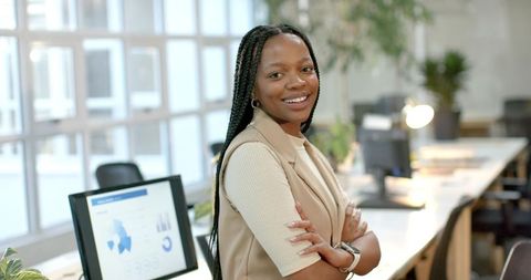 Confident African American businesswoman standing smiling arms crossed in coworking office