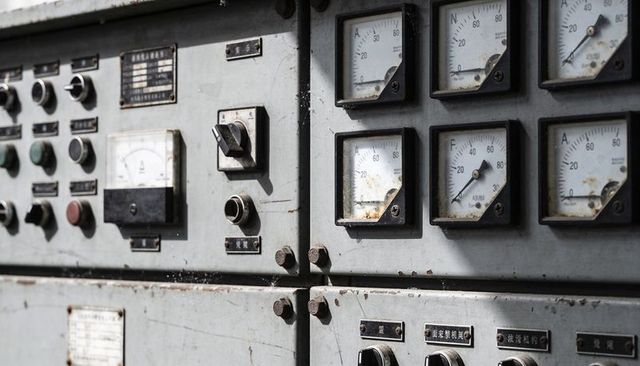 Vintage industrial control panel with analog gauges, rusted dials and toggle switches