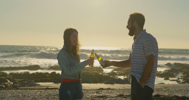Young couple toasting beer bottle at beach on a sunny day. Smiling happy couple 4k