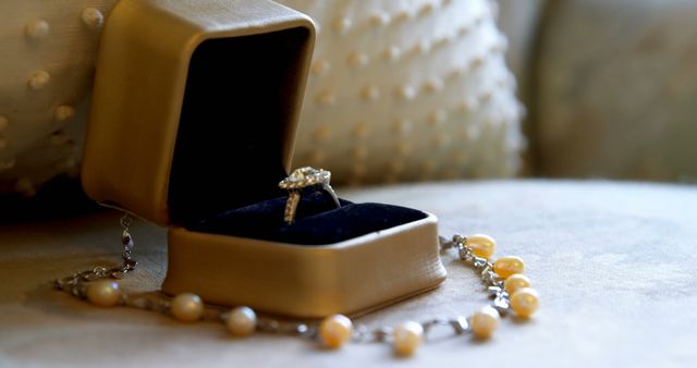 Close up of wedding ring in box with pearl necklace on pillow. Wedding, celebration and jewellery.