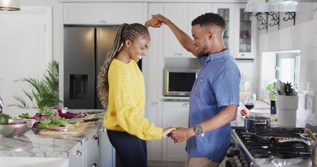 Young couple dancing joyfully in a modern kitchen. Perfect for lifestyle, home living, and relationship themes. Ideal for advertisements promoting home products, kitchenware, or romantic dating services.