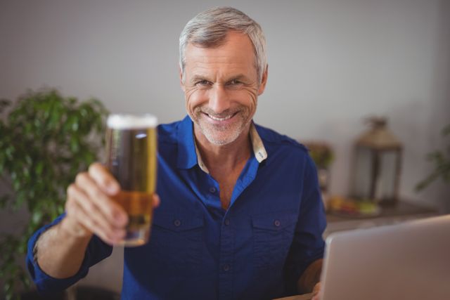 Portrait of mature man holding beer glass in restaurant