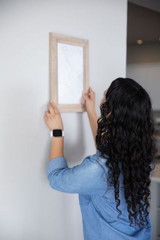 Woman adjusting picture frame in minimalist home with elegance