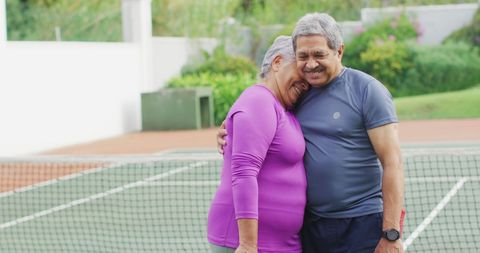 Senior Couple Embracing on Tennis Court Celebrating Active Retirement