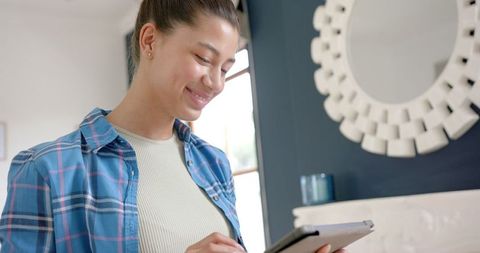 Joyful Teenage Girl Engaging with Tablet at Home