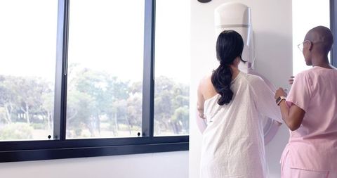 Radiology Technologist Positioning Patient for Mammogram Breast Screening in Sunlit Clinic