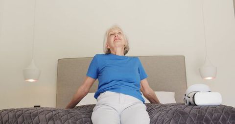 Senior woman finding relaxation in modern bedroom with vr headset