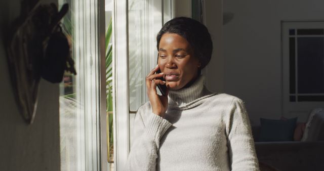 Afro-Caribbean Woman Talking on Smartphone Near Sunlit Window - Download Free Stock Images Pikwizard.com