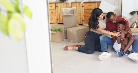Family unpacking boxes and hugging on floor, sharing joyful moment during move