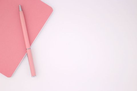 Pastel Pink Notebook with Matching Pen on White Surface
