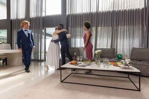 Diverse couple celebrating wedding reception in modern living room