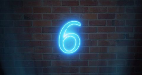Neon blue number six casting cyan halo on red-brown brick wall night urban glow