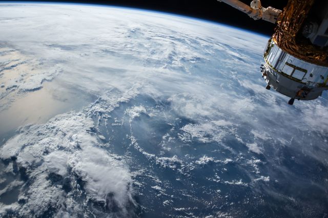 Stunning view of Earth's atmosphere with clouds and a satellite. Ideal for educational materials, space exploration articles, technology presentations, and science documentaries.